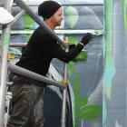 Street artist Ian Ross works on a wall at Heritage Coffee in Vogel St yesterday. Photo: Gregor...