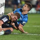 Highlanders second five-eighth Tei Walden, in the tackle of Blues winger Matt Duffie, grounds the...