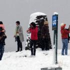 Falling snow and slush failed to stop tourists from taking photos at the Crown Range summit car...