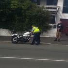 A Police officer examines a motorcycle after its rider lost control and came off, injuring himself in Dunedin. Screengrab: George Block