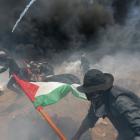Palestinian demonstrators run for cover from Israeli fire and tear gas during a protest against...