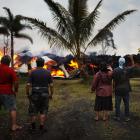 Community members watch as a home is destroyed by lava from a Kilauea volcano fissure in Leilani...