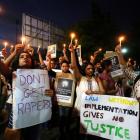 People hold candles and placards during a protest against the rape of an eight-year-old girl and...