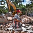 A man carries a picture of Indonesian President Joko Widodo from a school damaged by the August 5...