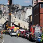 Firefighters and rescue workers stand at the site of a collapsed Morandi Bridge. Photo: Reuters