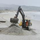An excavator digs for damaged sand bags torn from the base of the protective sand sausage at St...