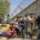 Reporters and military personal take shelter behind a truck during the attack on a military...