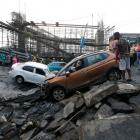 People stand next to the wreckage of vehicles at the site of a bridge that collapsed in Kolkata....