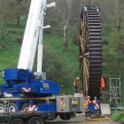 The newly-restored historic Phoenix Mill water wheel is lifted into place at its original site in...