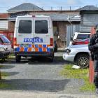 A member of the armed offenders squad stands guard outside a yard in Bathgate St which, alongside...