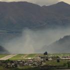 A plume of smoke from a controlled burn-off hovers over the eastern approach to Queenstown...