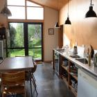 The kitchen-dining area has glass doors at both ends, visually expanding the space into the...