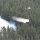 A helicopter with a monsoon bucket fights a fire at a hillside in Hawea. Photo: Mark Price