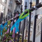 About 50 ribbons, signed with messages by victims and their supporters, were tied to the gates of...