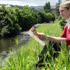 Dunedin Botanic Garden information services officer Clare Fraser sits beside the Water of Leith...