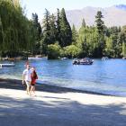 A couple strolls along Queenstown beach.