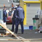 Police inspect items strewn across the driveway of a Dunedin storage facility belonging to a man...