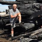 Surveying the charred remains of timber consumed in the Burnside fire is Valley Lumber owner...