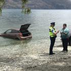 An American tourist talks to police after her rental car rolled into Lake Wakatipu yesterday....