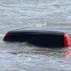 A police officer who declined to be named examines a car submerged at the Vauxhall Yacht Club...