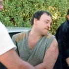 Arthur Taylor is escorted from the back of a police vehicle at the Tairua Police station in 1998...