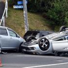A police officer inspects a car on its roof on Kenmure Rd in Dunedin yesterday. PHOTO: PETER...