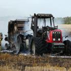Firefighters stand by after extinguishing a tractor and stubble fire in a Waiwera South paddock...