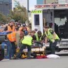 Spectators watch as motorcyclist Tony Campbell, of New Plymouth, lies on the track after crashing...