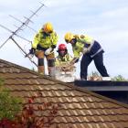 Firemen break down a chimney in a bid to gain access to a contractor, whose arm was pinned when...