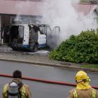 Smoke clouds the front of the van as fire crews attempt to extinguish the fire. Photo: Sean Nugent