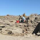 University of Otago archaeological dig team Peter Mitchell excavates the interior of a large...