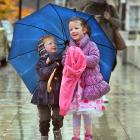 Siblings Eli (2) and Isobel (4) McConnell share an umbrella as they walk to daycare near the...