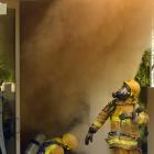Firefighters crawl out of a smoke-filled house in Queenstown’s Lancewood Lane yesterday morning....
