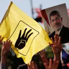 People flash Rabia signs as they hold a picture of former Egyptian president Mursi during a...