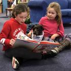 Megan De Cort (12, left) and Emma Magee (6) read to Petal the St John/SPCA Outreach Therapy pet...