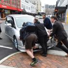 Passers-by help push a vehicle off the street following the crash. Photo: Gregor Richardson