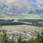 Lake Hawea township - showing bare land in the top half of the photograph beyond pine trees,...