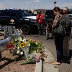 People look at flowers placed at the site of a mass shooting where 20 people lost their lives at...