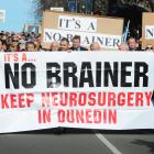 Marchers hold up a signs during a protest to keep neurosurgery services in Dunedin. Photo: ODT files