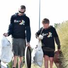 David Heads and son Aiden (11), of Dunedin, carry rubbish from the sand dunes at St Kilda during...
