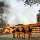 Firefighters look on as a house burns in the wildfires north of San Francisco Bay, California....