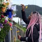 Tasha Gweshe (23), a student from a neighbouring flat, places flowers in the hedge at the flat in...