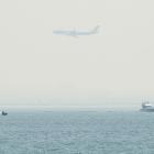 A plane flies over smoke-covered Botany Bay as it comes in to land at Sydney airport, while fires...