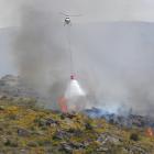 A helicopter discharges a monsoon bucket over the scrub fire. PHOTO: ADAM BURNS 
