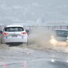Motorists negotiate an area of surface flooding on Portobello Rd, near the Cove, yesterday...