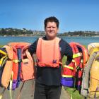 Richard Warrington, of Read Marine, wearing a life jacket from the 1980s, holds life jackets...
