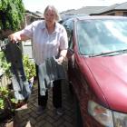 Flora Smith holds the remains of her destroyed right front mudguard while her car bears the scars...