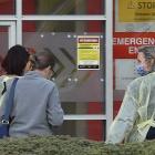 Dunedin Hospital staff wearing protective gear escort two patients through the main entrance of...