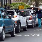 People wait in a large line of cars, hoping to receive a flu vaccine in Mosgiel yesterday. PHOTOS...