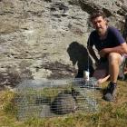 Forest &amp; Bird volunteer Billy Stephen Barton beside a feral cat caught in a satellite...